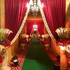 an elaborately decorated hall with red drapes and floral arrangements