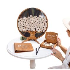 a woman sitting in front of a table holding an open box with a tree on it