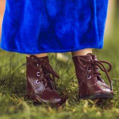 a close up of a person's feet wearing brown shoes and blue pants in the grass