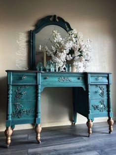 a blue vanity with flowers on it and a mirror