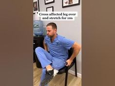 a man sitting in a chair with his foot on the ground while wearing blue scrubs