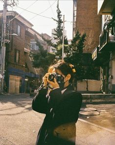 a woman taking a photo with her camera on the street in front of some buildings