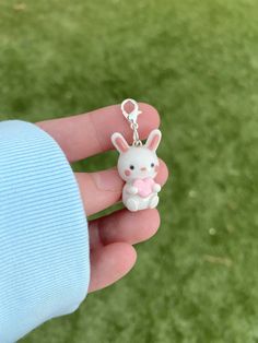 a person holding a small keychain with a bunny on it's back