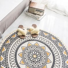 two slippers are placed on the floor in front of a round rug with an intricate design