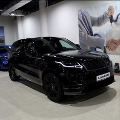 a black range rover parked in front of a large poster