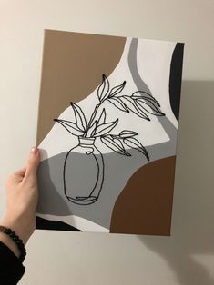 a person holding up a piece of art that looks like a vase with flowers in it