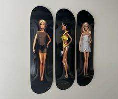 three barbie dolls are displayed on skateboards