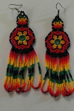 two pairs of beaded earrings are hanging from hooks on a white surface, one is red and the other is yellow