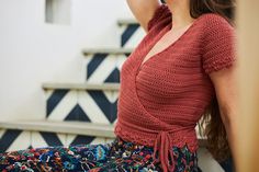 a woman is sitting on the stairs talking on her cell phone while wearing colorful pants and a red top