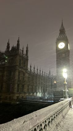 the big ben clock tower towering over the city of london at night in the snow