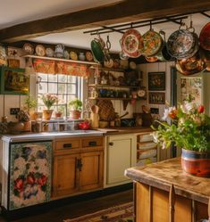 a kitchen filled with lots of pots and pans hanging from the ceiling next to a window