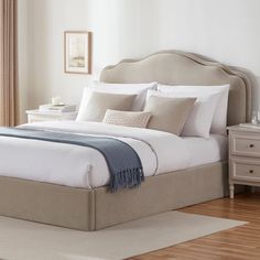 a bed with white linens and pillows in a bedroom next to a wooden floor