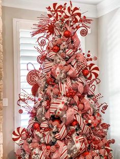 a red and white christmas tree decorated with candy canes, candies and bows