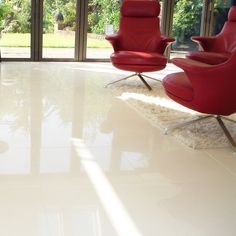 an empty room with two red chairs and a white rug on the floor in front of large windows