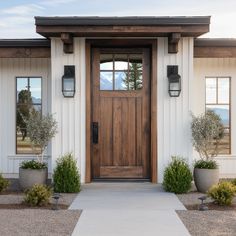 the front door of a home with two potted plants on each side and an entry way leading to it