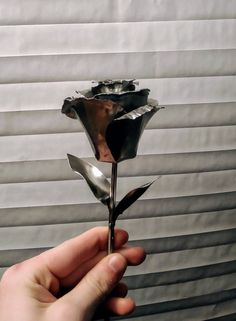 a person is holding a metal flower in their hand