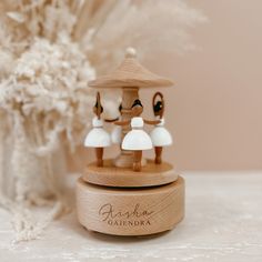 three wooden figurines are on top of a small stand with flowers in the background