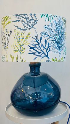 a blue vase sitting on top of a white table next to a lampshade