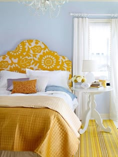 a bedroom with yellow and white bedding, pillows and headboard on the wall