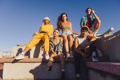 group of young people sitting on concrete steps in front of blue sky with no clouds