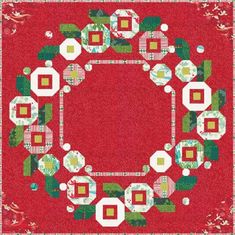 a red and green christmas wreath quilted on top of a tablecloth with white flowers