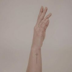 a person's hand with a cross tattoo on the middle of their left arm