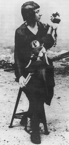 an old black and white photo of a woman sitting on a chair holding a teddy bear