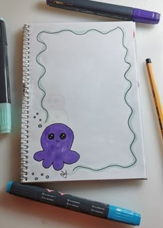 a notebook with an octopus drawn on it next to some markers and pencils,