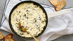 a pan filled with cheese and bread on top of a white towel next to slices of bread