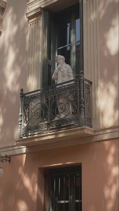 a balcony with a statue on the balconies and an open window above it