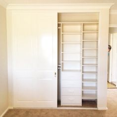 an empty room with white closet doors and shelves