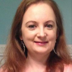 a woman with red hair is smiling at the camera while wearing large silver hoop earrings