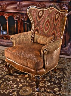 an old chair sitting on top of a rug in front of a wooden fireplace mantel