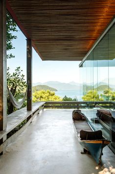 a bench sitting on top of a cement floor next to a glass wall and wooden ceiling