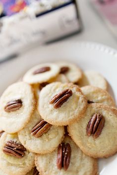 a white plate topped with cookies and pecans on top of a table next to a book