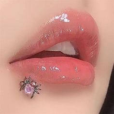 a woman's lips with pink glitter and a spider brooch on her lip