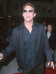 a man in black jacket and sunglasses standing on red carpet with his hands out to the side