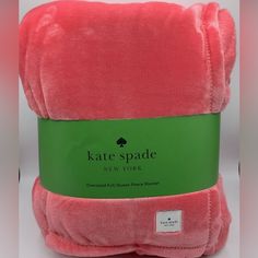 a pink blanket with a green label on it that says kate spade new york