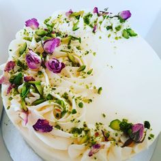 a white cake with purple flowers and green sprinkles