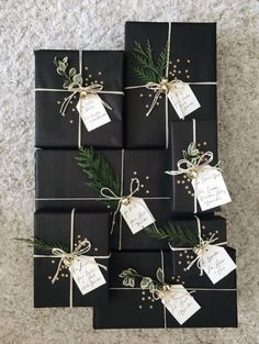 black wrapped presents tied with twine and pine needles are sitting on the floor next to each other