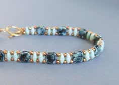 a beaded bracelet with blue and white beads is shown on a gray surface,