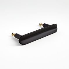 a pair of black handles on a white surface with two gold knobs in the middle