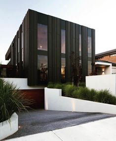 a modern house with black and white sidings on the outside, surrounded by greenery