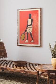 a painting hangs on the wall next to a table with a basket and lamp in it