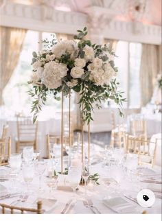 there are many flowers in tall vases on the long table at this wedding reception