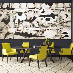 a dining room table with yellow chairs and a large painting on the wall behind it