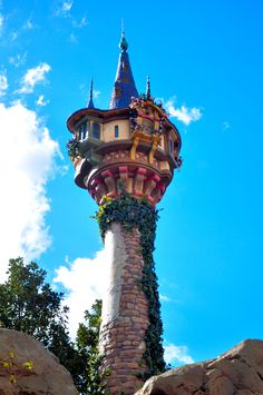 a tall tower with plants growing out of it's sides on top of rocks