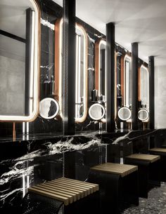 a row of sinks and mirrors in a room with black marble flooring on the walls