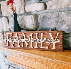 a wooden family name sign sitting on top of a mantle next to a vase with flowers