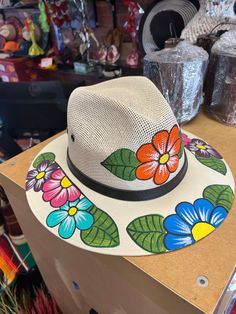 Hand painted floral hat, with different multicolor flowers. White Floral Print Beach Hat, Multicolor Fedora With Curved Brim For Rodeo, Multicolor Fedora With Short Brim For Rodeo, Multicolor Floral Print Hats For Spring, Summer Multicolor Flower Hat, Summer Multicolor Flower-shaped Hat, Multicolor Short Brim Fedora For Rodeo, Multicolor Floral Print Spring Hats, Spring Multicolor Floral Print Hats